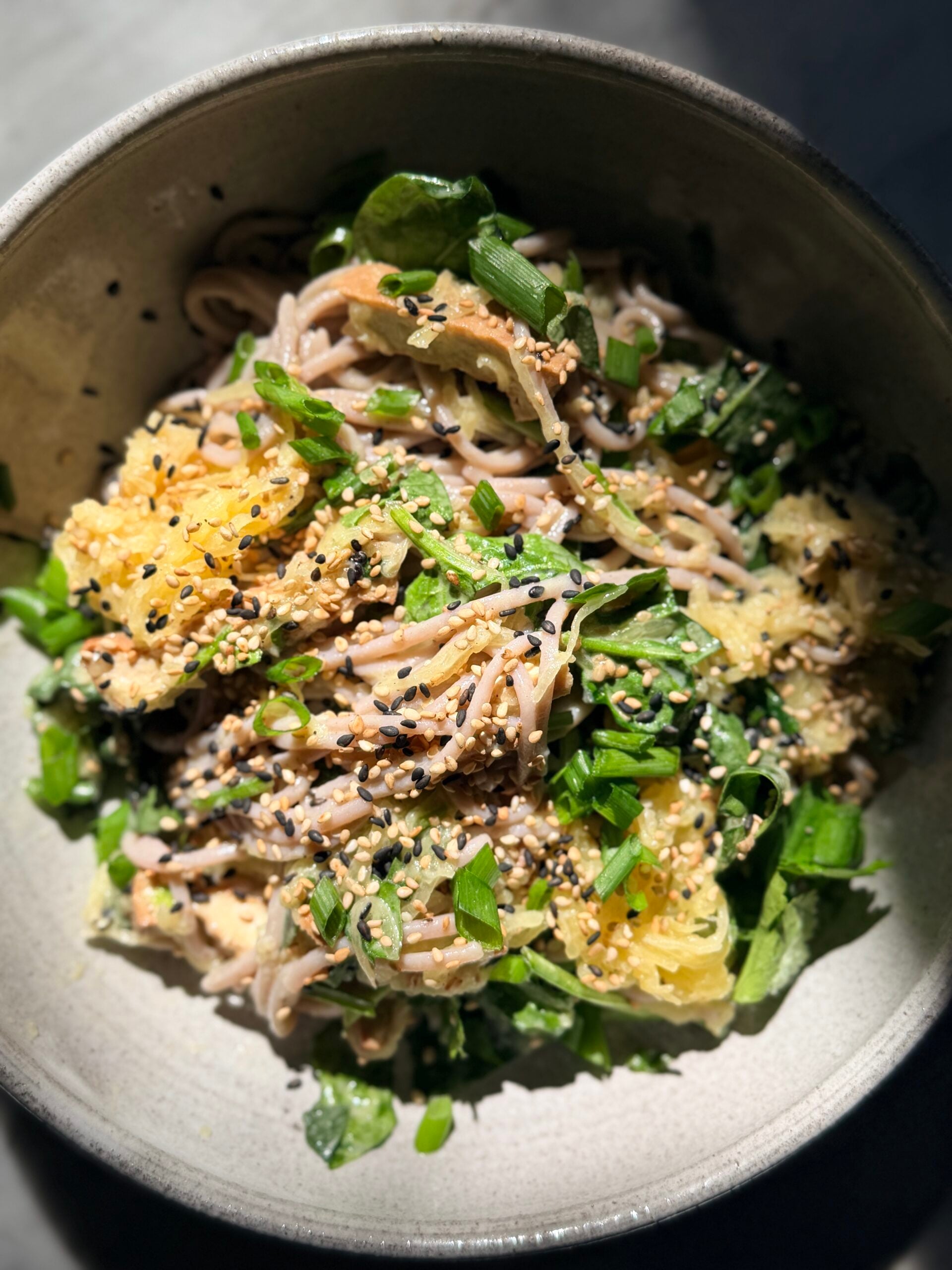 A bowl of soba noodles with spaghetti squash, chopped scallions, and black and white sesame seeds. - Hetty Lui McKinnon