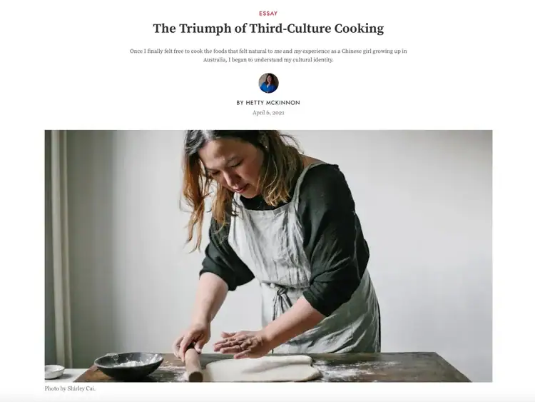 A woman wearing an apron rolls out dough on a floured table, with a bowl and measuring cup nearby. Photo by Shirley Cai.